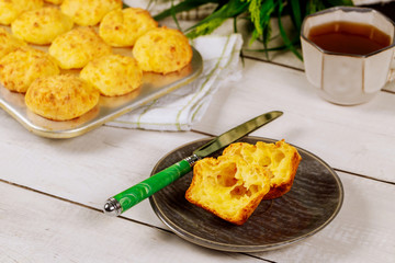 Cut brazilian cheese bread on plate with knife.