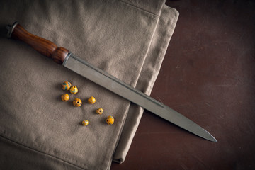 Viking dirk (dagger) arranged on a linen tunic with glass beads
