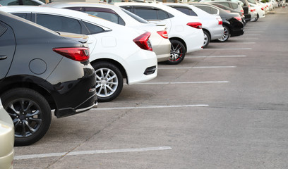 Closeup of rear, back side of black car with  other cars parking in outdoor parking area.