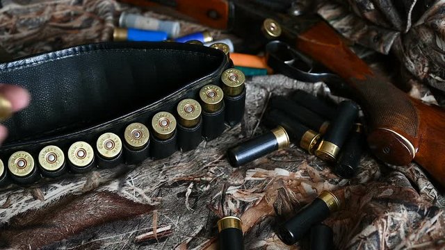 Shotgun cartridges and an old shotgun are on camouflage fabric.