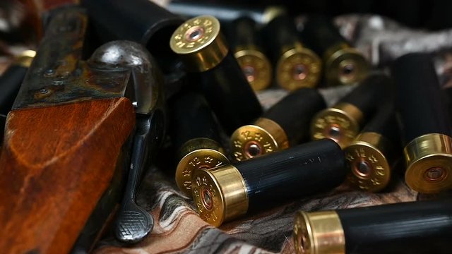Shotgun cartridges and an old shotgun are on camouflage fabric.