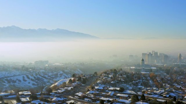 Aerial pan over inversion filled valley revealing SLC Capitol Building Downtown