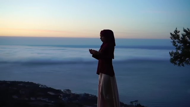 Muslim woman prays. Salat Al-Fajr prayer dawn, before sunrise. Fasting in the Holy month of Ramadan. Beautiful nature, sky and sea background