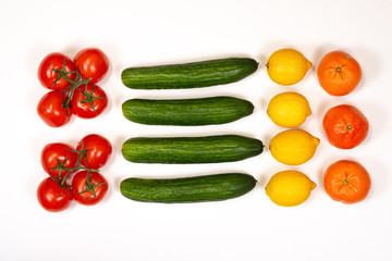 Red tomatoes on a branch and green cucumbers on a white background, top view
