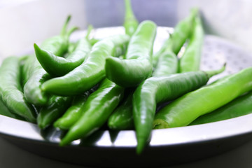 bunch of fresh green chili peppers on a white background