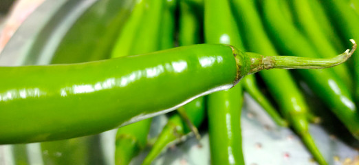 Full frame close up of a bunch of bright and shiny green chili peppers. Organic vegetables at the local food market.