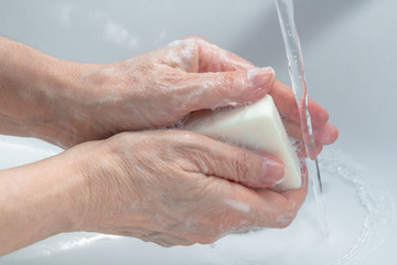 Washing of hands with soap under running water.