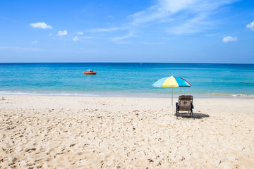 Relaxing on the beach on summer holiday break, outdoor day light, paradise island, beach chair undr umbrella looking at blue sea