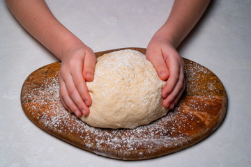 kid hands knead yeast dough for pizza or pie