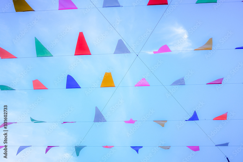 Wall mural triangle colorful flags decoration at party or temple fair with blue sky background