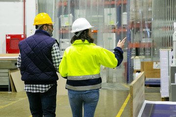 Back view of employees walking at factory and pointing to right. Rear view of confident machine operators looking aside. Print manufacturing concept