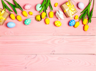 Fototapeta na wymiar Easter border from eggs, decorations and tulips on pink wooden background.