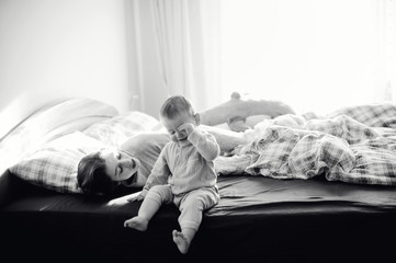 Cheerful baby boy having fun on bed with his elder sister in cute cozy pijamas in mpnpchrome