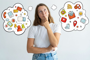 Woman looking upwards with hand drawn social media sketches. Thoughtful pretty lady standing and touching mouth. Contemplation concept. Isolated front view on background with icons.