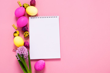 Fototapeta na wymiar Happy easter concept. Festive spring layout of eggs clean notebook flowers on a pink background. Copy space.
