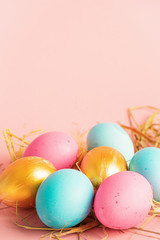 Happy easter concept. large small eggs of various fashionable colors lie in a heap on a pink background. Copy space