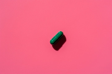 Close-up of one pill lies on a pink surface