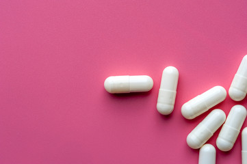 Obraz na płótnie Canvas Close-up of white pills lie on a pink surface