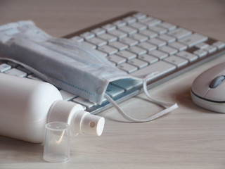 Fototapeta na wymiar Sanitizer for processing desktop, keyboard, mouse close up and face mask. Sanitation of the workplace at home and in the office during the corona virus pandemic, cavid-19.