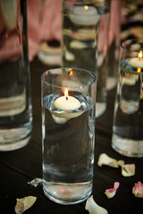 Aroma candle in glass, flower petals on floor