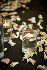 Aroma candle in glass, flower petals on floor