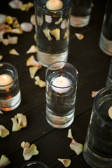 Obraz na płótnie Canvas Aroma candle in glass, flower petals on floor