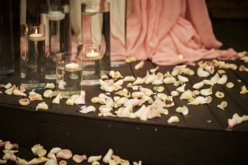 Aroma candle in glass, flower petals on floor