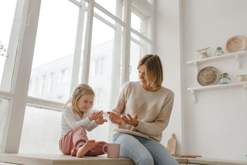 A young mother spends time with her little daughter at home.