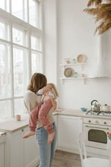 A young mother spends time with her little daughter at home.