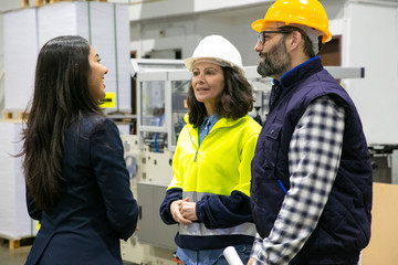 Confident technicians talking with smiling office manager. Group of professional employees talking...