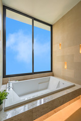 Fototapeta na wymiar Modern clean bathtub interior building with sand stone wall and wall lamp light decoration, concept bathroom