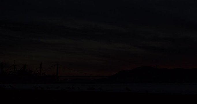 Beautiful orange sunset in San Fransisco with Golden Gate Bridge in Background Silhouet of seagulls, time lapse