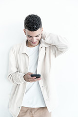 Smiling young man using mobile phone. Portrait of handsome happy young man using smartphone and looking down on grey background. Technology concept