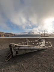 old wooden boat at whalers bay south shetland islands antarctica with old sailing vessel bark europa in the background, expecition to antarctica  © Christoph