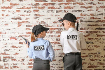 Obraz na płótnie Canvas Cute little police officers on brick background