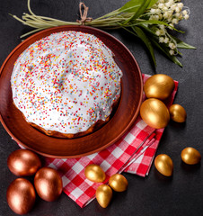 Easter eggs gold and bronze and Easter cake on a dark background