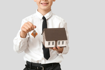 Little real estate agent with model of house on light background