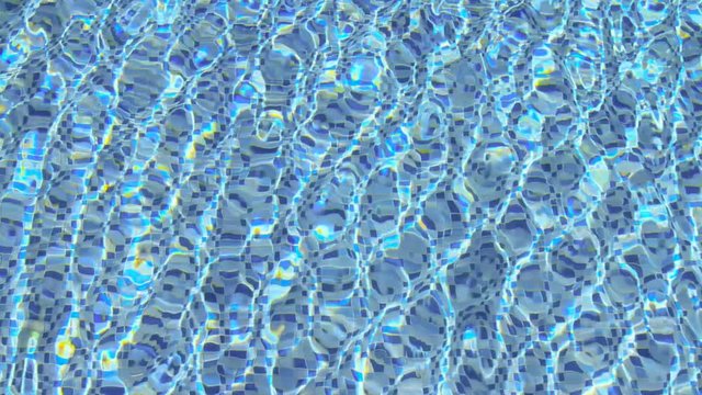 Ripple and clear water in a swimming pool with reflection from sunrise blue sky background.