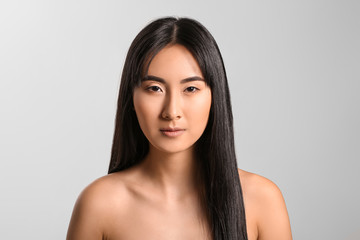 Obraz na płótnie Canvas Young Asian woman with beautiful long hair on grey background
