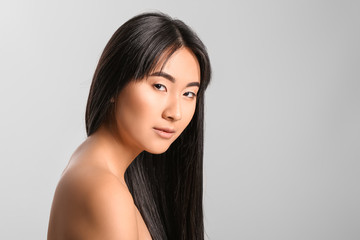 Naklejka premium Young Asian woman with beautiful long hair on grey background