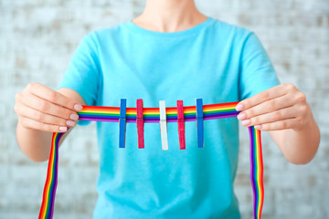 Woman holding rainbow ribbon with pegs. Concept of transgender