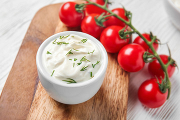Tasty sour cream and tomatoes on white wooden table