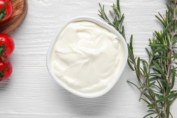 Bowl of tasty sour cream on wooden table