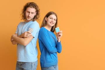 Young couple with oral erectile dysfunction medication and condom on color background