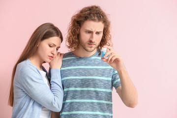 Sad young couple with oral erectile dysfunction medication on color background