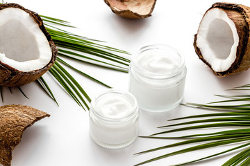 Face care. Coconut cream in glass jar on white background