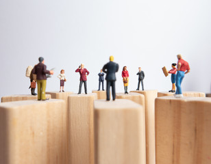 Side view of miniature toys standing on wooden block - social distancing, anti-social or team work...