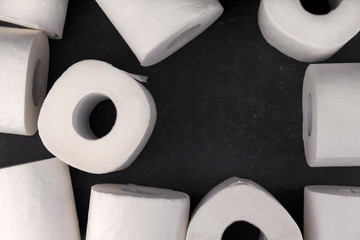 .White toilet paper rolls on a dark gray background copy space. Shortage of toilet paper.