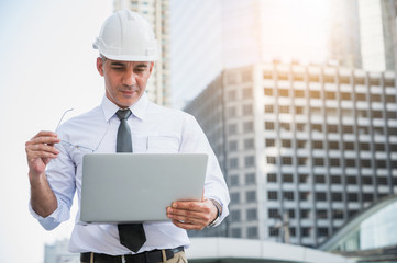 Civil engineering using laptop while working on building construction site.