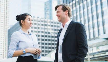 Business people man and woman standing and talking in urban city background.
